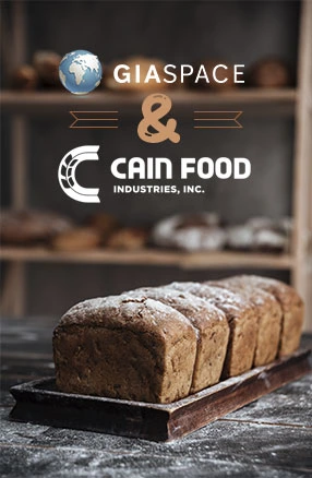 Bread loaf cooling on a tray in a bakery, with GIASPACE and Cain Food Industries branding above — signaling a collaboration in food production.