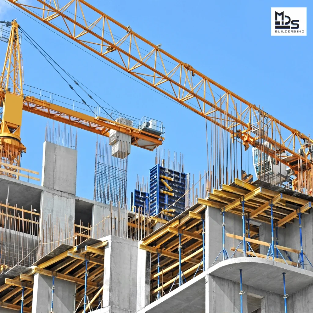 Construction site with a large yellow crane over a partially built concrete structure and exposed rebar.