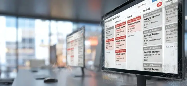 Office workspace with multiple monitors displaying a color-coded help-desk ticket queue on screen(s).